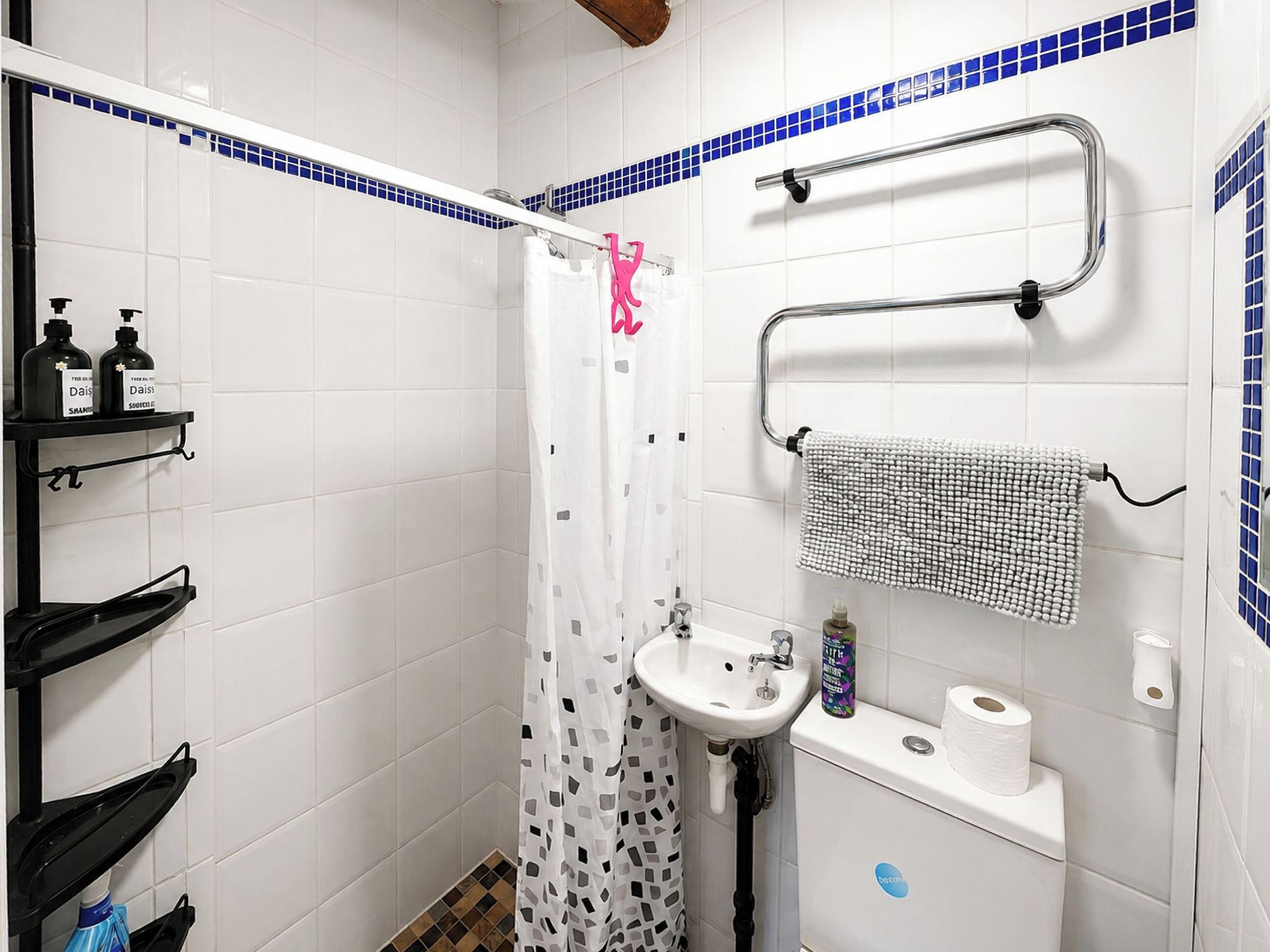 A bathroom with white tiles, a shower curtain, a sink, a toilet, and a towel rack.