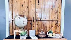 A wooden desk with a globe, a potted plant, a sign, and a basket with fruits. - Lakewoods Cottage (Howard)