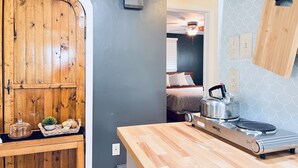 A compact kitchen with a wooden countertop, a Nesco induction cooktop, and a wooden cabinet. - Lakewoods Cottage (Howard)