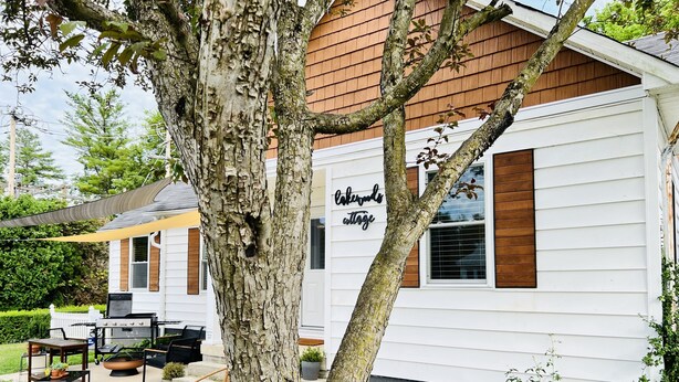 A house with a sign reading "Lakeview Cottage" and a patio area with outdoor furniture. - Lakewoods Cottage (Howard)