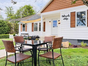 Un espace extérieur abrité avec des chaises en osier et une table, une terrasse en bois et un bâtiment sur lequel est apposée une enseigne indiquant « Gâteaux et douceurs ».