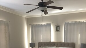 Une chambre à coucher comprenant un lit, un ventilateur de plafond, deux lampes de chevet et une table de chevet.