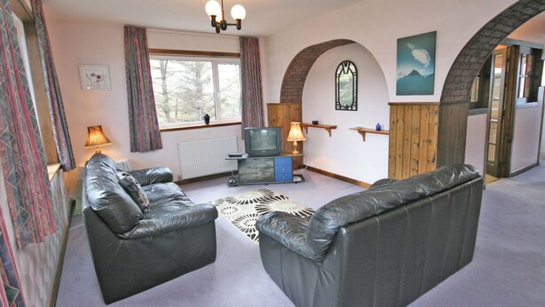 A living room with two leather sofas, a television, and a fireplace.
