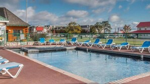A swimming pool with blue lounge chairs and a flagpole with an American flag. - Mackinac Lodge (Mackinaw City)