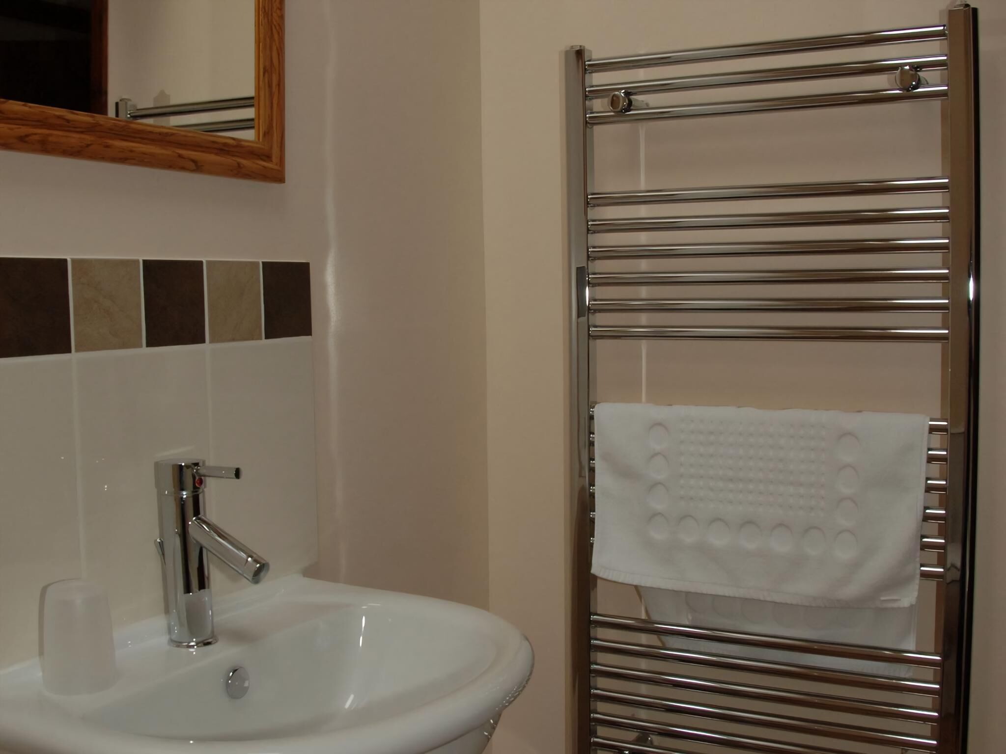 A bathroom with a white sink, chrome faucet, and a towel rack with a white towel.