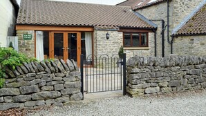 A stone cottage with a tiled roof, a wooden door, and a stone wall entrance.