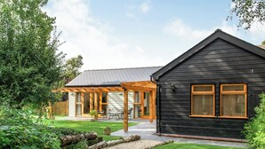 Une maison dotée d’un patio couvert, d’une façade noire et d’un jardin bien entretenu.