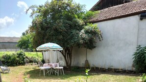A backyard with a white wall, a tree, and a small garden area. - Appartement au Calme Proche des Commerces au Bord de la Loire (Decize)