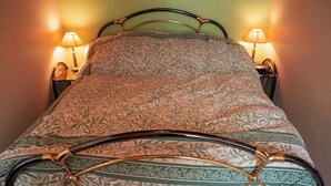 A neatly made bed with a patterned bedspread, two bedside lamps, and a metal headboard. - Appartement au Calme Proche des Commerces au Bord de la Loire (Decize)