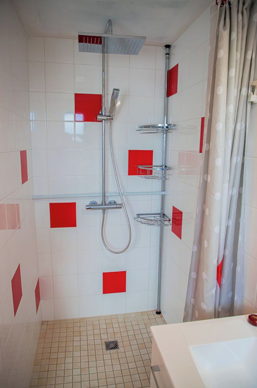 Une douche équipée d’un pommeau de douche à main et d’un pommeau fixé au mur, ainsi qu’un porte-serviettes et un sol carrelé.