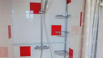 Une douche équipée d’un pommeau de douche à main et d’un pommeau fixé au mur, ainsi qu’un porte-serviettes et un sol carrelé.