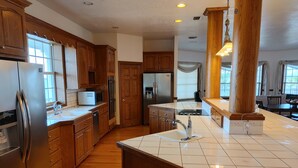 A spacious kitchen with wooden cabinets, a stainless steel refrigerator, and a large island with a sink.