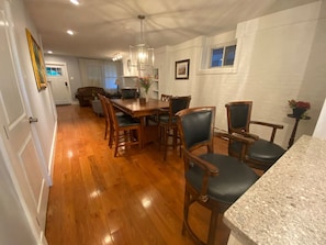 Enjoy meals in this dining area with a long table and six chairs, surrounded by a polished floor and white walls.