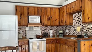 A kitchen with wooden cabinets, a white stove, a microwave, and a coffee maker.