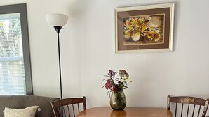 A dining area with a round wooden table, two chairs, and a vase of flowers.