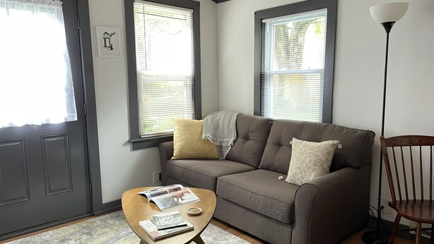 A living room with a sofa, a coffee table with magazines, and a floor lamp.