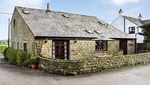 A stone house with a sloped roof, a wooden door, and a small porch area.