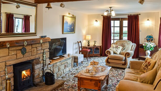 A cozy living room with a stone fireplace, comfortable seating, and a television.