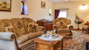 A traditional living room with a sofa set, a wooden coffee table, and a floral-patterned rug.