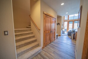 A staircase leading to a wooden door, a hallway with wooden flooring, and a view of a balcony with outdoor furniture. - Antlers Gulch 104 (Keystone)