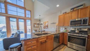 A modern kitchen with wooden cabinets, stainless steel appliances, and large windows overlooking a deck. - Antlers Gulch 104 (Keystone)