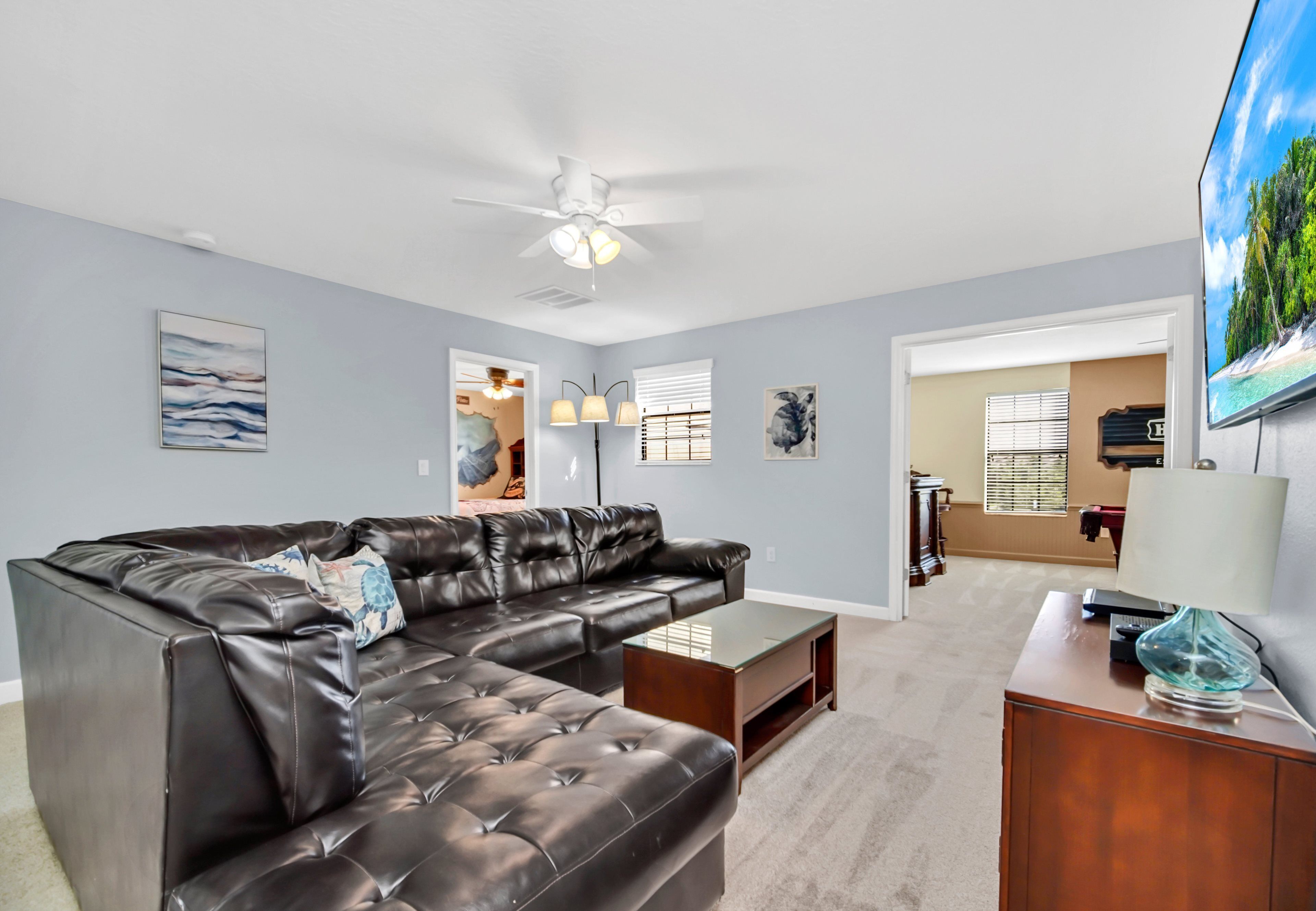 A living room with a sectional sofa, a coffee table, a TV, and artwork on the walls.