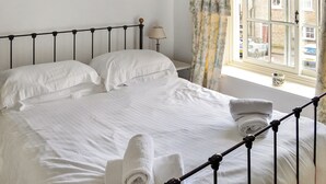 A neatly made bed with white linens, a metal headboard, and a window with curtains. - 2 bedroom accommodation in Richmond (Richmond)