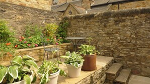 A stone courtyard with potted plants, a table, and chairs. - 2 bedroom accommodation in Richmond (Richmond)