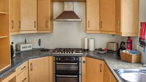 A compact kitchen with wooden cabinets, a gas stove, an oven, and a sink. - 2 bedroom accommodation in Richmond (Richmond)