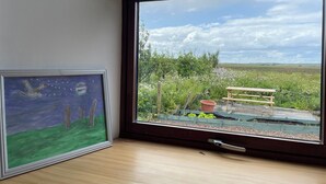 A room with a large window overlooking a garden with a wooden bench and a potted plant. - You will love everything about Mey Bee. (Mey, near Thurso)