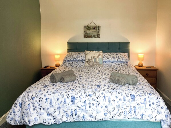 A bed with a floral pattern, two bedside lamps, a headboard, and a wall-mounted picture.