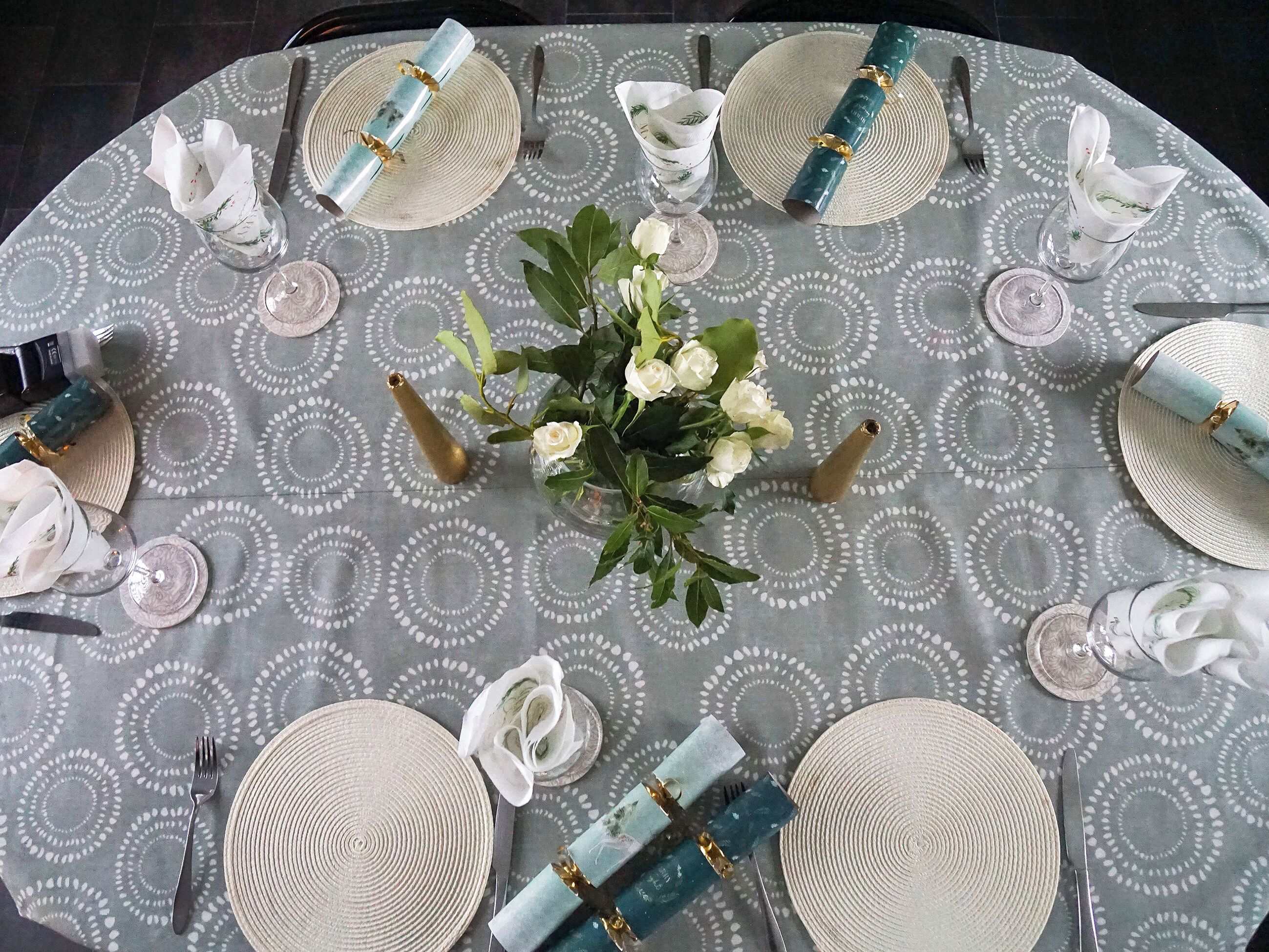 A round table set with plates, cutlery, and napkins, surrounded by a patterned tablecloth.