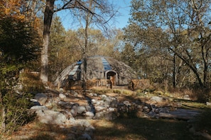 A geodesic dome structure surrounded by trees and rocks.