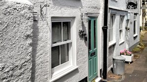 A white building with a green door, windows, and a small flower box on the ground. - 1 bedroom accommodation in Dartmouth (Dartmouth)