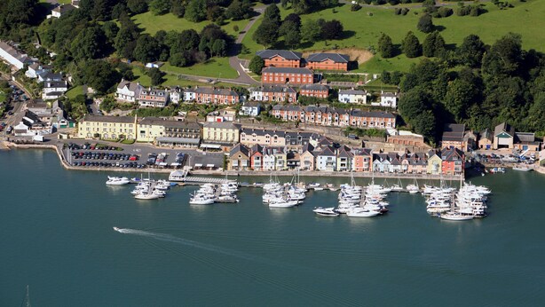 A marina with numerous boats docked, a large building with red and white facades, and a residential area with colorful houses. - 1 bedroom accommodation in Dartmouth (Dartmouth)
