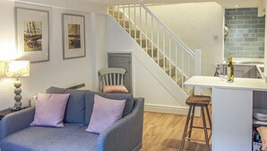 A modern living room with a grey sofa, a wooden floor, a staircase, and a kitchen area with a bar counter. - 1 bedroom accommodation in Dartmouth (Dartmouth)