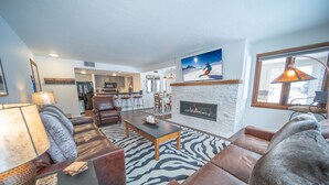A living room with a fireplace, leather sofas, a zebra-patterned rug, and a television mounted on the wall. - Quicksilver 1605 (Keystone)