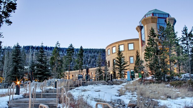 A hotel with a curved building, outdoor stairs, and snow-covered ground. - Quicksilver 1605 (Keystone)