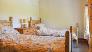 Une chambre à coucher avec deux lits en bois, une table de chevet avec une lampe et une commode.