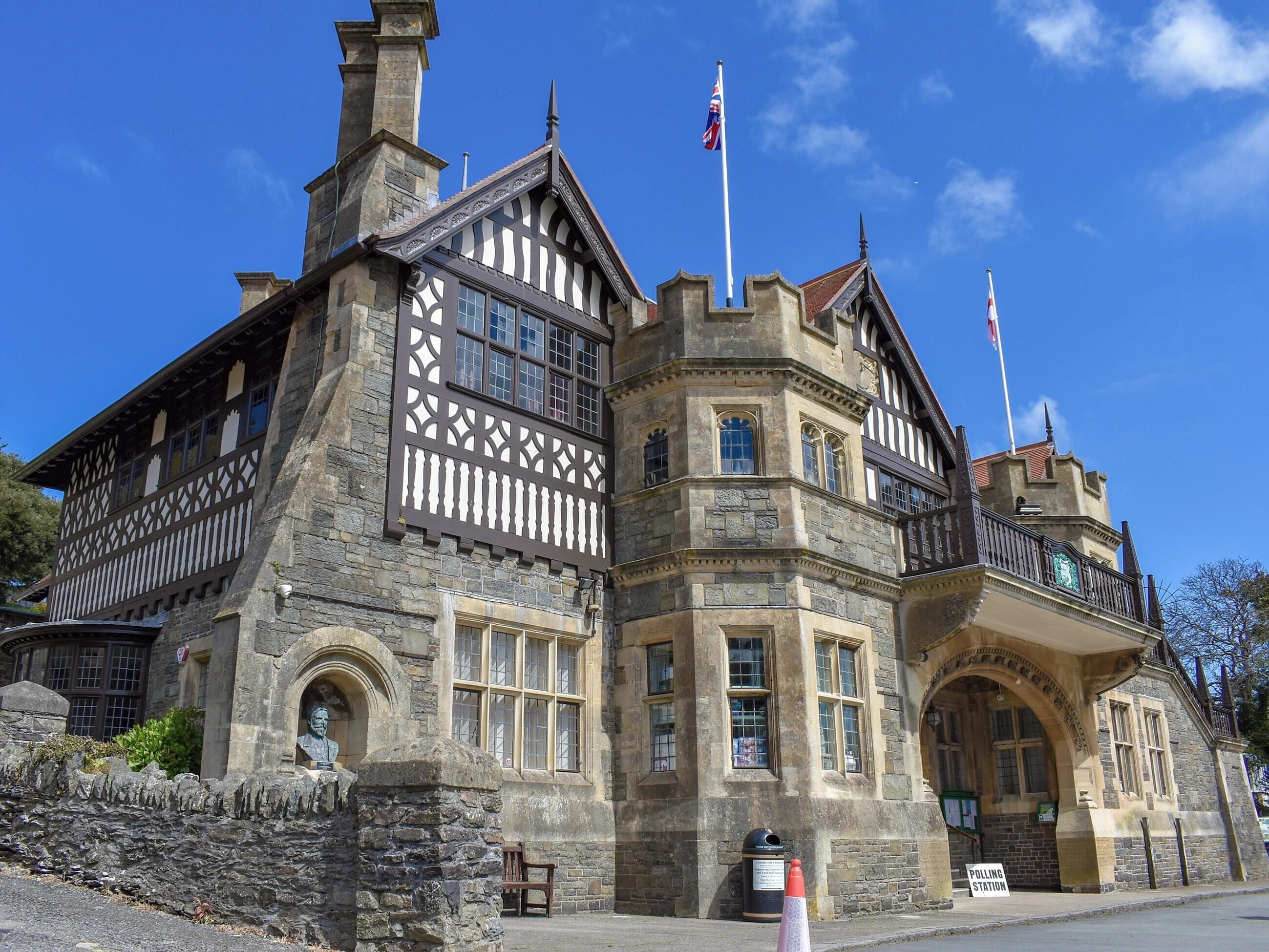 A historic building with a stone facade, multiple windows, and a flagpole.