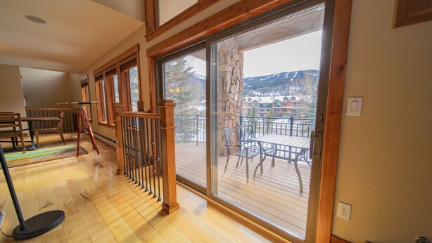 A spacious room with a wooden floor, large sliding glass doors leading to an outdoor deck with a view of a mountainous landscape. - Enclave 29 (Keystone)