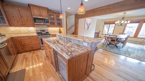 A spacious kitchen with wooden cabinets, a granite countertop, and a large island. - Enclave 29 (Keystone)