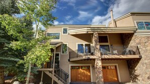 A two-story house with a stone facade, a balcony, and a garage. - Enclave 29 (Keystone)