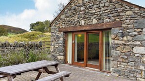 A stone building with a wooden door and a picnic table outside. - 2 bedroom accommodation in Dockray, near Ullswater (Dockray, near Ullswater)