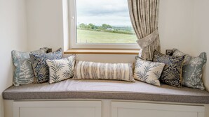 A window seat with a view of a field, a curtain, and patterned cushions. - Willow Tree Cottage - UK35893 (Ludchurch, near Narberth)
