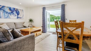 A modern living room with a sofa, coffee table, and dining table. - Willow Tree Cottage - UK35893 (Ludchurch, near Narberth)