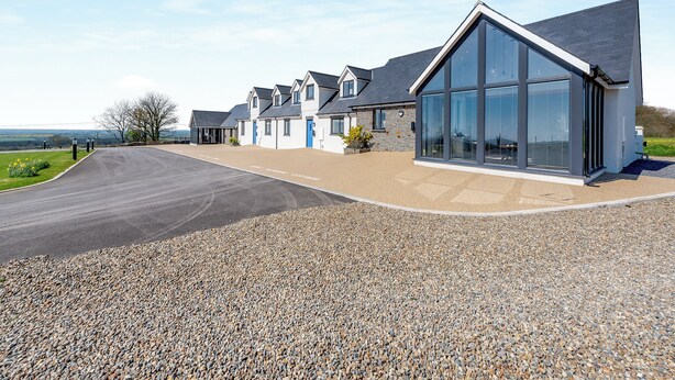 A modern building with large windows, a gravel driveway, and a stone facade. - Willow Tree Cottage - UK35893 (Ludchurch, near Narberth)