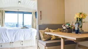 Quarto com uma cama, uma mesa de cabeceira com um vaso de flores e vista para o exterior.