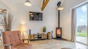 Una sala de estar moderna con un sofá, un televisor, una chimenea y un ventanal grande.