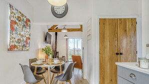 Un comedor con una mesa redonda, sillas, un reloj y una puerta de madera.